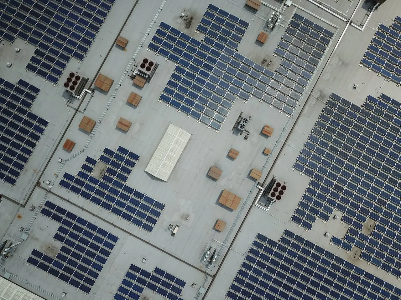 High-angle aerial shot of a large rooftop solar panel array on an industrial building.